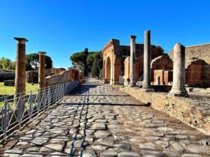 L'immagine mostra il Decumano Massimo all'interno degli scavi archeologici del Parco Archeologico di Ostia Antica, l'antico porto di Roma situato alla foce del Tevere.