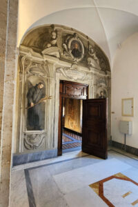 L'immagine mostra l'ingresso al celebre corridoio illusionistico delle Camerette di Sant'Ignazio di Loyola a Roma, decorato con affreschi in prospettiva (trompe-l'œil) realizzati da Andrea Pozzo tra il 1682 e il 1685
