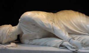 The image depicts the headless, recumbent body of Saint Cecilia, carved in white marble, contained beneath the main altar inside a black marble niche